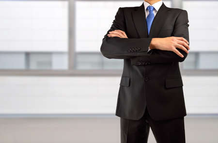 cropped shot of businessman with arms crossed against at officeの写真素材