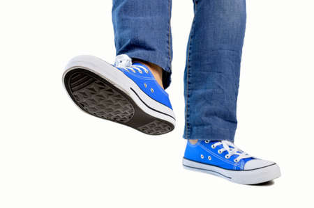 close up of steps of a person with sneakers and jeans walking isolated white backgroundの写真素材