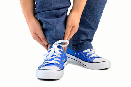 cropped shot of a man with sneakers and touching his ankles isolated on white background