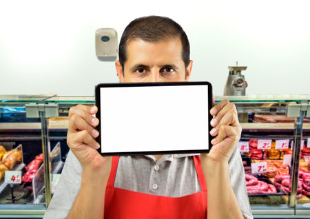 shopman holding a tablet against her mouth at the butchery