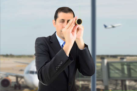 businessman entrepreneur looking through spyglass searching travel and offers opportunities at airport departure loungeの写真素材
