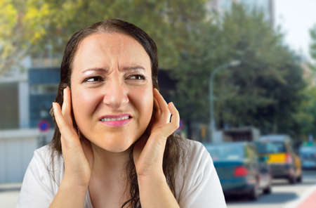 woman covering her ears with her hands at cityの写真素材