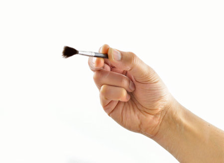 Closeup of a hand holding a brush and painting on glass