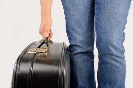Close up hand of a man picking up an old black suitcase with a white backgroundの写真素材