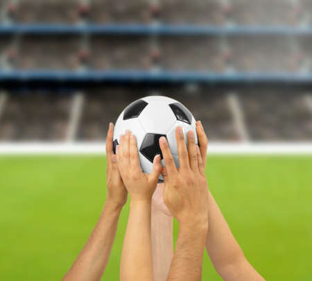 Group of football players holding a soccer ball at football stadiumの写真素材