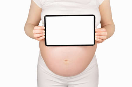 A cropped image of a pregnant woman holding up a digital tablet with a blank screenの写真素材