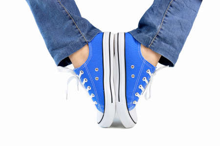 Cropped image of a person wearing sneakers standing on their toes as ballet position isolated with white backgroundの写真素材