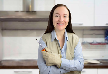 Portrait of a handyman woman smiling with screwdriver in hand and crossed arms at the kitchen