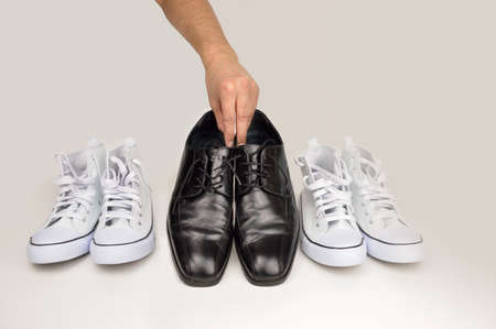 Cropped shot of a man grabbing his formal shoes from amongst his running shoesの写真素材