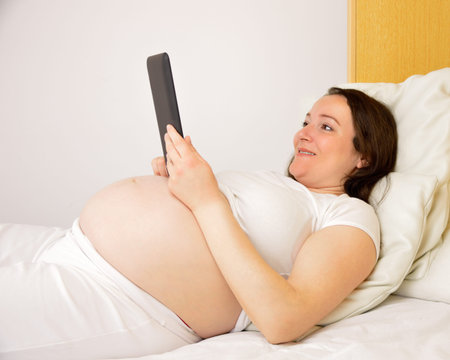 Pregnant woman using a digital tablet at homeの写真素材