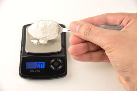 Drug dealer weighing a drug in a digital scaleの写真素材