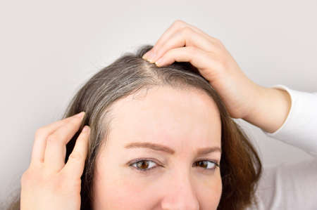 woman is checking white hair while looking at the mirrorの写真素材
