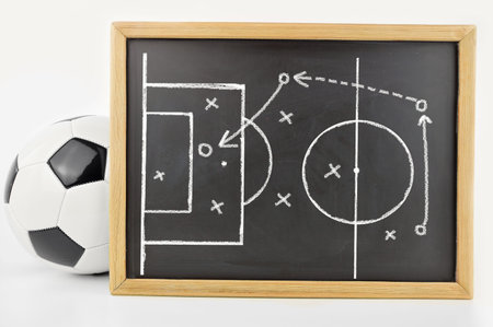 graphic a tactics of soccer game with white chalk on blackboard next to the soccer ball isolated on white backgroundの写真素材