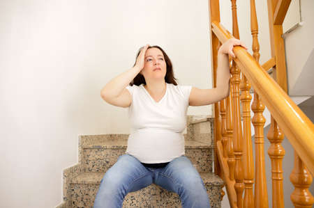 A pregnant woman struggling with morning sickness in the staircaseの写真素材