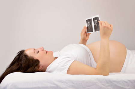 Pregnant woman looking at a sonogram picture at home