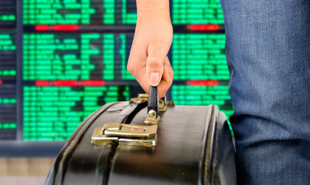 Close-up hand of a woman picking up an old black suitcase  at international airport with the flight...