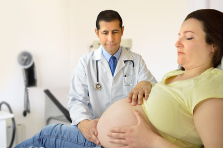 Doctor feeling the position of the fetus in his pregnant patient 