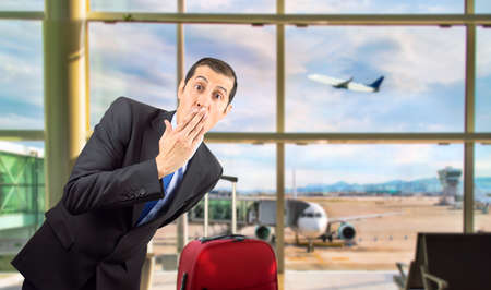 portrait of businessman covering his mouth with hand at airport departure loungeの写真素材