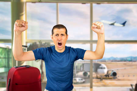 Portrait of an excited tourist with hands raised at the airportの写真素材