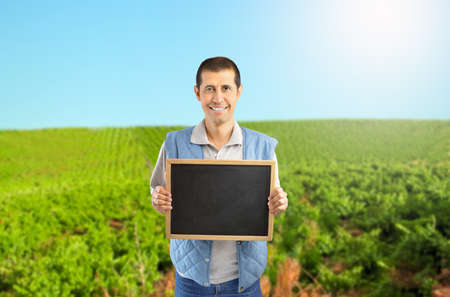 farmer holding an empty chalkboard in a vineyard at Spain with copy spaceの写真素材