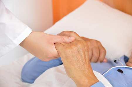 Closeup shot of hands clasped in unity and comfort on a hospital bedの写真素材