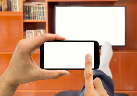 Relaxed man with smartphone connected to a tv and copy space
