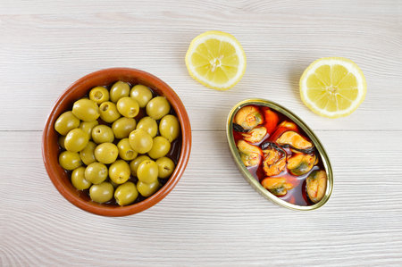 Tin of mackerel and olives on a table on rustic wooden tableの写真素材