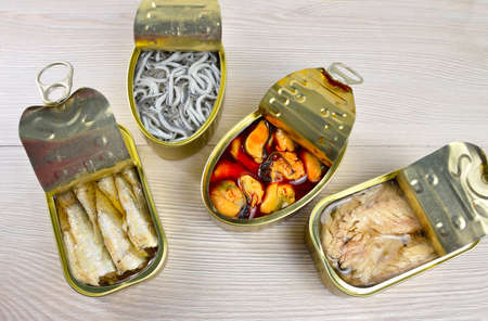 Assortment of cans of canned with different types of fish and seafood on rustic wooden tableの写真素材