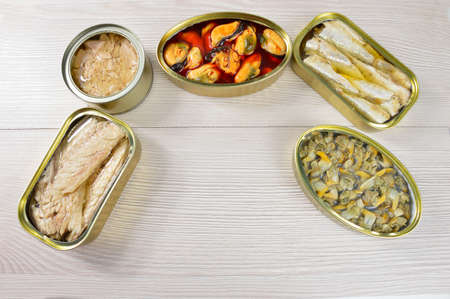 Assortment of cans of canned with different types of fish and seafood on rustic wooden tableの写真素材