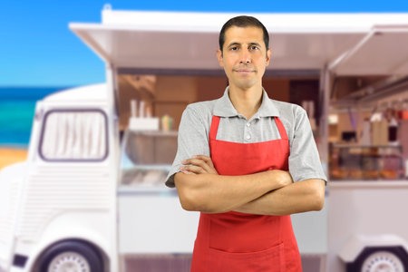 Smiling ice cream car employee with apron at beach