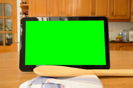 Tablet on wooden surface next a cloth and wooden kitchenware isolated cutout on green background with chroma keyの写真素材