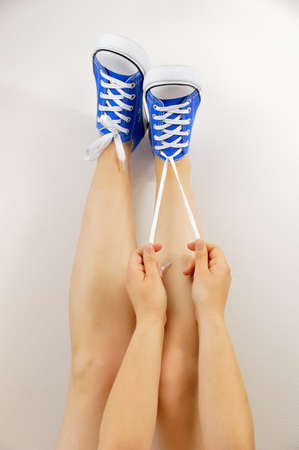 closeup of young woman knotting sneakers with wall backgroundの写真素材