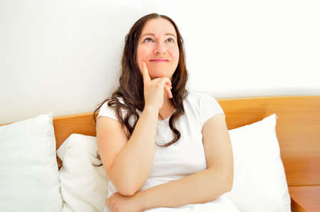 close up of woman thinking and looking up at bedroomの写真素材