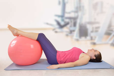 Shot of an attractive young woman working out with an exercise ball at gymの写真素材