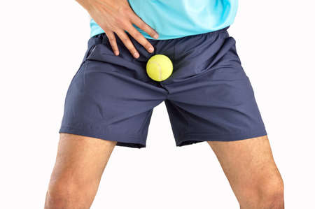 man playing tennis being hit by a tennis ball with force in the crotch when he misses a catch or as an unexpected accident on a clay court.Isolated in whiteの写真素材