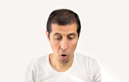 Portrait of a shocked young man looking down against a white backgroundの写真素材