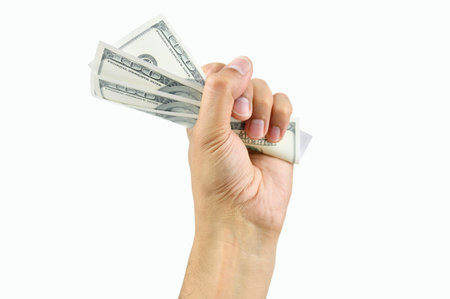 Closeup of a man's hand crushing a wad of hundred dollar notes while isolated on a white background