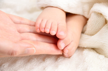 Cropped close up shot of a mother holding her baby's foot