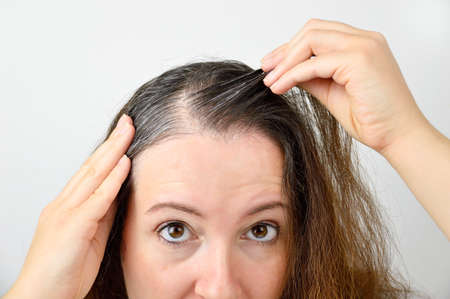 woman is checking white hair while looking at the mirrorの写真素材