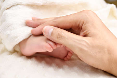 Cropped close up shot of a father holding her baby's footの写真素材