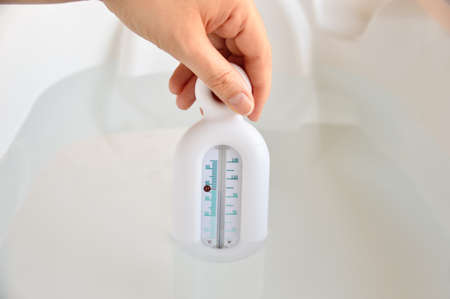 Close-up of hand of a mother checking the water temperature of the child's bathtubの写真素材