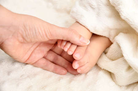 Cropped close up shot of a mother holding her baby's footの写真素材