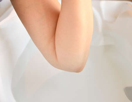 mother checking the water temperature of a child's bathtub with the elbowの写真素材