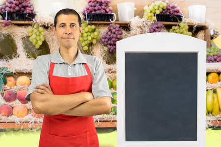 portrait of shopman at the fruits store with crossing arms with blackboardの写真素材