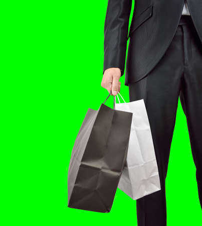 cropped shot of businessman in black suit and posing with shopping bags isolated cutout on green background with chroma keyの写真素材