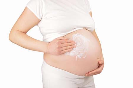 Cropped shot of a pregnant woman with suntan onto her belly against a white backgroundの写真素材