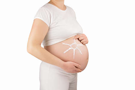 Cropped shot of a pregnant woman with the sun drawn onto her belly against the background whiteの写真素材