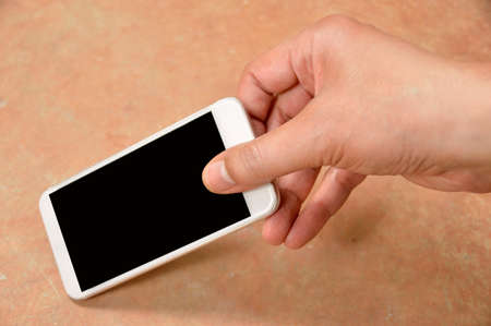 cropped shot of a man locating and catching a phone on the floor at homeの写真素材