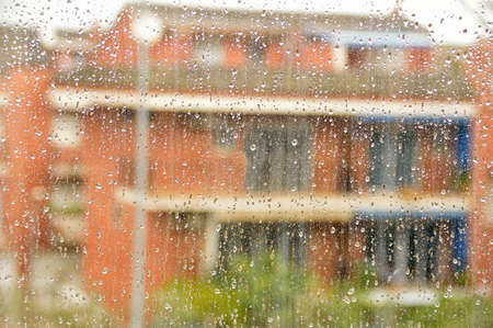 Water drops on glass with city backgroundの写真素材