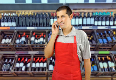 shopman with apron using a smart phone at a wineryの写真素材